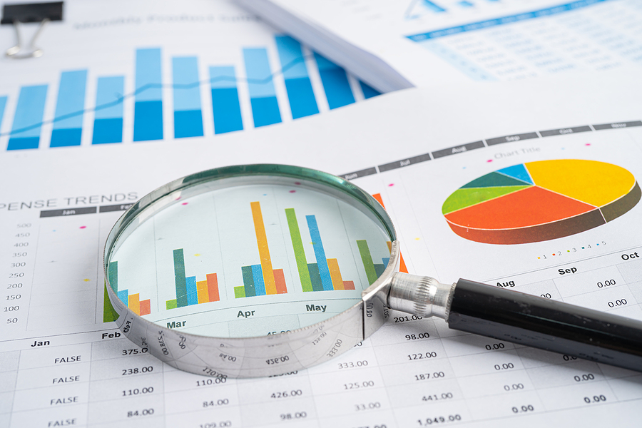 Magnifying glass on charts graphs paper. Acumatica Budgeting concept.