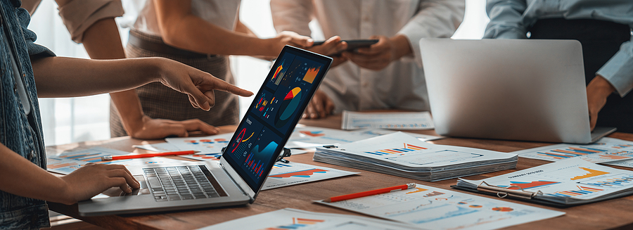 group of people in office with laptops and graphs